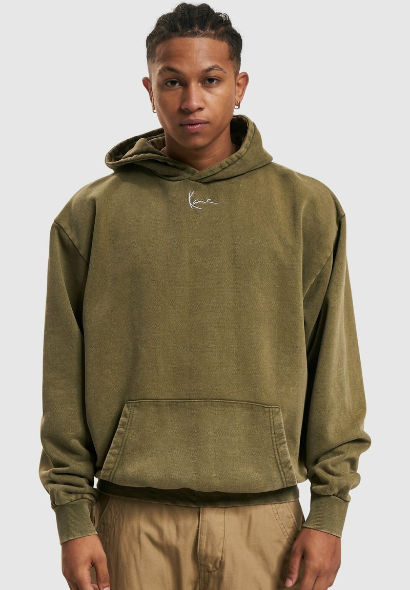 Sweat à capuche vert olive avec une coupe décontractée, poche avant, poignets côtelés et un petit logo blanc sur la poitrine. Matériau en mélange de coton.