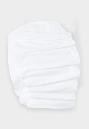 Drap-housse blanc avec bords élastiques, soigneusement plié sur une surface claire.