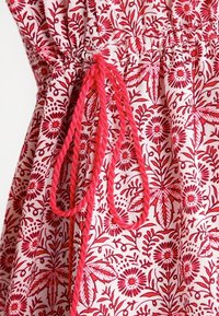 Bavlna se květinovým vzorem v bílé a červené barvě, s elastickým pasem a růžovými tkanými akcenty. Design zahrnuje listy a květiny.