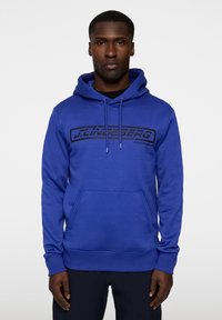 Felpa blu realizzata in misto cotone, con tasca a marsupio davanti e cappuccio regolabile con cordino. Grafica del logo nera sul petto.