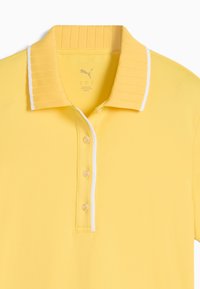 Polo giallo realizzato in tessuto morbido. Presenta un colletto a costine con accenti bianchi e una patta con tre bottoni, dal design elegante.