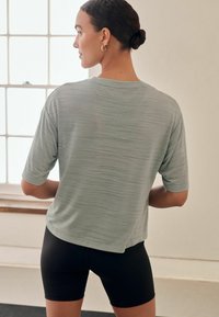 Lichtgroene T-shirt met korte mouwen, een gestructureerde afwerking, een relaxed fit en een ronde halslijn, gecombineerd met zwarte shorts.