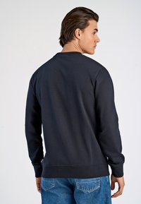 Marinefarbener Rundhals-Sweatshirt aus Baumwollmischung, mit gerippten Bündchen und Saum, glatter Textur und minimaler Nahtdetail auf der Rückseite.
