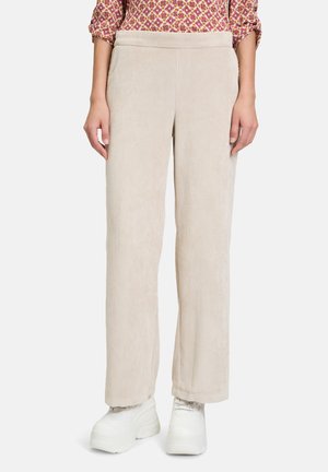 Beige Cord-Hosen mit geradem Bein-Design und strukturiertem Finish. Kombiniert mit weißen Plateauschuhen.