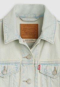 Γαλάζιο τζιν μπουφάν με κλασικό γιακά, δύο τσέπες στο στήθος, ασημί κουμπιά και καφέ δερμάτινη ετικέτα μάρκας στο εσωτερικό.