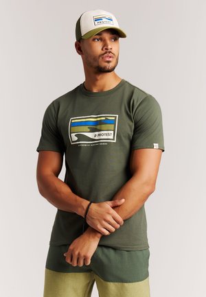 Olivgroen T-shirt met een gedrukt ontwerp van blauwe en gele golven. Gecombineerd met lichtgroene broek, met een casual pasvorm.