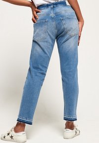 Ljusblå denimjeans med rak benform, fram- och bakfickor samt synliga sömnadsdetaljer. Har en avskuren fåll och en urblekt textur.