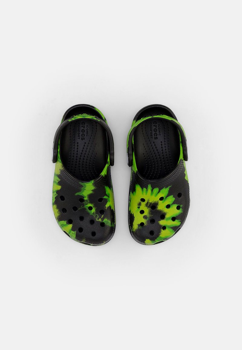 Pareja de Crocs de color negro y verde neón con diseño tie-dye, con agujeros de ventilación y correas ajustables en el talón, sobre un fondo blanco.