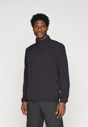 Schwarze Zip-Jacke mit hohem Kragen, elastischen Bündchen, zwei Seitentaschen und kleinem CK-Logo auf der Brust. Glattes, leichtes Material.