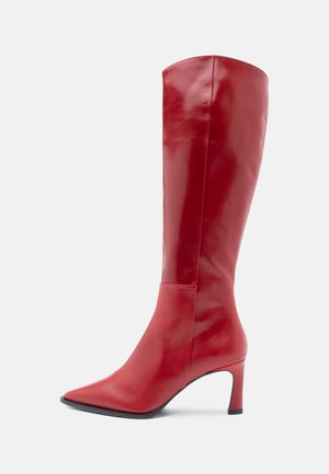 Tall red leather boot with pointed toe and curved mid-height heel, shown from side on plain light background.