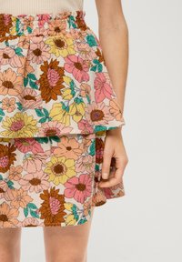 Jupe à motif floral avec un design plissé, présentant des couleurs vives comme le rose, le jaune et le marron, fabriquée en tissu léger avec une taille élastique.