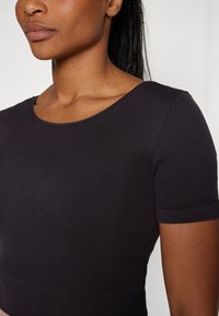 Black short-sleeve ribbed top with a round neckline, fitted design, and smooth texture. No notable patterns or accents.