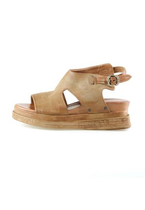 Bruine suède open-toe sleehak met zijuitsparingen, verstelbare enkelband en gestructureerde zool op een witte achtergrond.