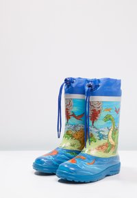 Multikleurige regenlaarzen met een blauwe bovenkant, voorzien van een dinosaurusscène. Gemaakt van glanzend materiaal, met een gestructureerde blauwe zool en blauwe veters.