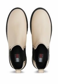 Stivali alla caviglia in pelle beige con suole in gomma nera, pannelli laterali elasticizzati e cuciture a contrasto. Presenta un tassello sul tallone.