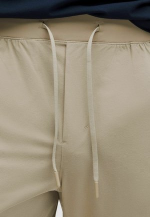 Beige trousers with a smooth texture, featuring a waistband with drawstrings and beige tips. The fabric appears lightweight and slightly stretchy.