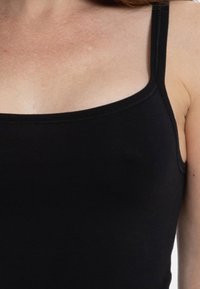 Black tank top featuring thin straps and a fitted design. Made from soft fabric with a smooth texture. No visible patterns or detailing.