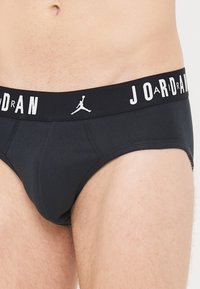 Schwarze Baumwollslips mit breitem Gummibund, auf dem in weißen Buchstaben "JORDAN" steht, und einem Jumpman-Logo in der Mitte.