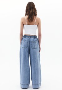 Vaaleansiniset leveät farkut, joissa on joustava vyötärö ja kaksi takataskua. Sileä pinta, rento tyyli ja löysä istuvuus.