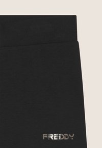 Leggings sportivi neri con elastico a coste e logo metallico "FREDDY". Tessuto morbido e design aderente.