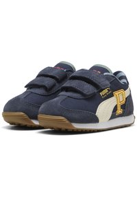 Tumesinine sneakersid, millel on nahast ja tekstiilist pealis, valge riba, takjakinnised, kollane logo ja kummist tald, millel on pidamisel olev mustri.