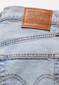 Jeans de denim azul claro com um patch de pele da Levi Strauss & Co. costurado acima do bolso traseiro.