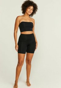 Svart off-shoulder topp och högmidjade shorts i slät, elastisk tyg. Outfiten har en sömlös design och minimalistisk stil.