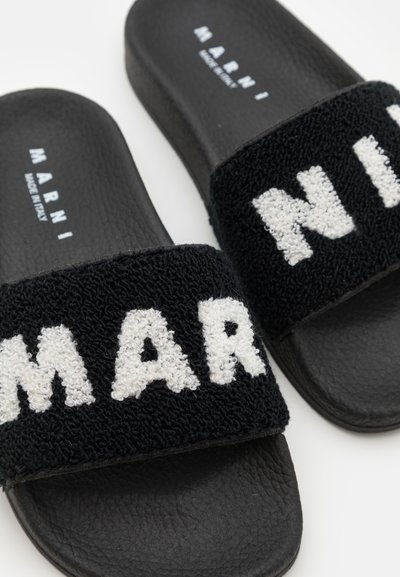 Ciabatte nere con cinturini in tessuto testurizzato nero che presentano "MARNI" in lettere bianche in peluche. Suole in gomma, design piatto, stile moderno.