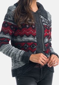 Cardigan se zipovým zapínáním, s šedým základem, červenými a černými geometrickými vzory, pletenou texturou a límcem.