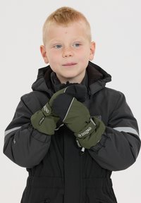 Moufles vertes et noires avec un marquage en zigzag, tissu texturé et accents réfléchissants. Portées par un enfant dans une veste sombre.