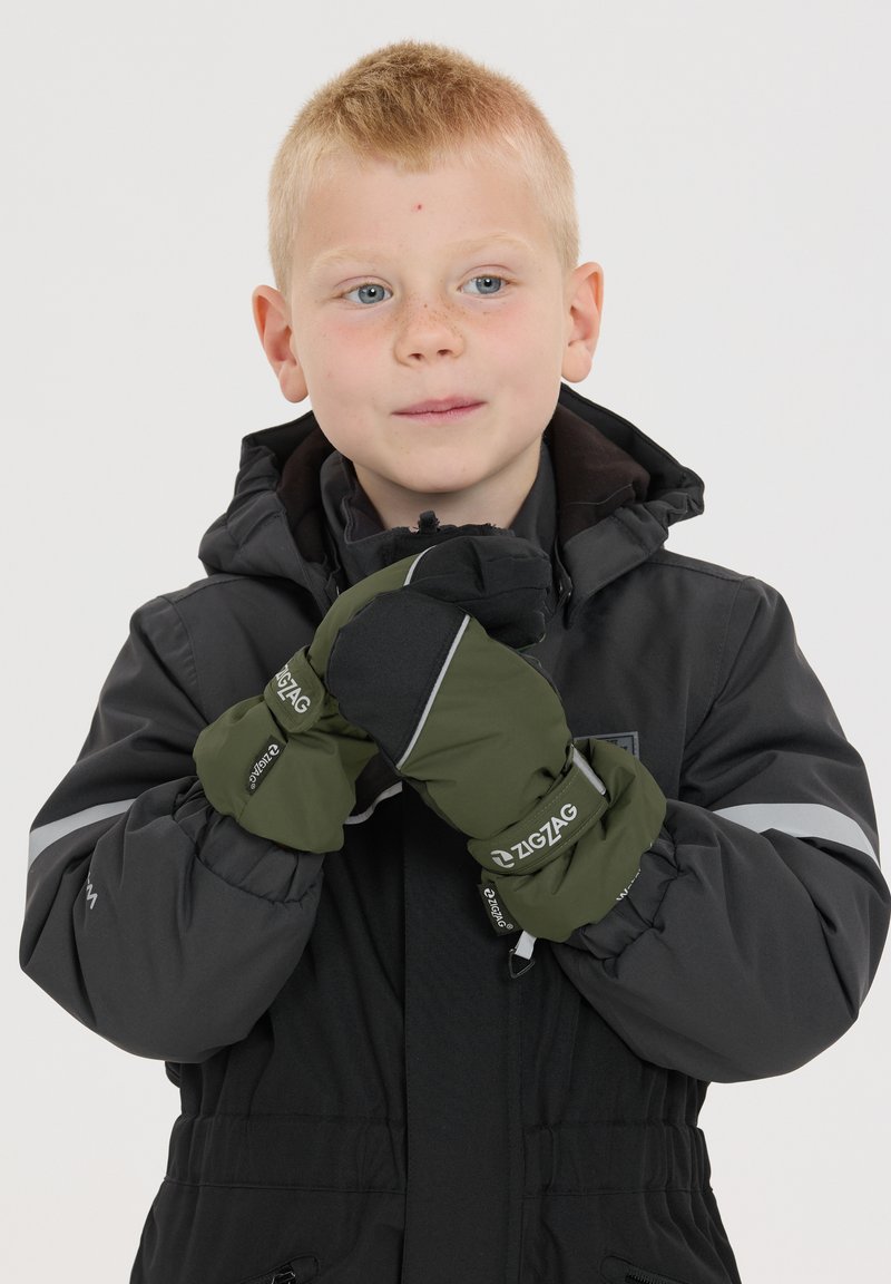 Moufles vertes et noires avec un marquage en zigzag, tissu texturé et accents réfléchissants. Portées par un enfant dans une veste sombre.