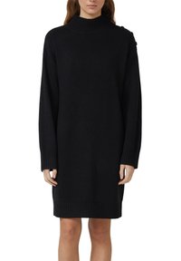 Zwarte gebreide jurk met een hoge geribde halslijn, lange mouwen en geribde manchetten en zoom. Beschikt over een ontspannen pasvorm.