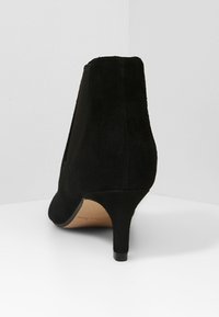 Svart mocka ankelskoboot med en avsmalnande klack, med en ren design och slät textur. Slip-on stil med elastiska sidpaneler.