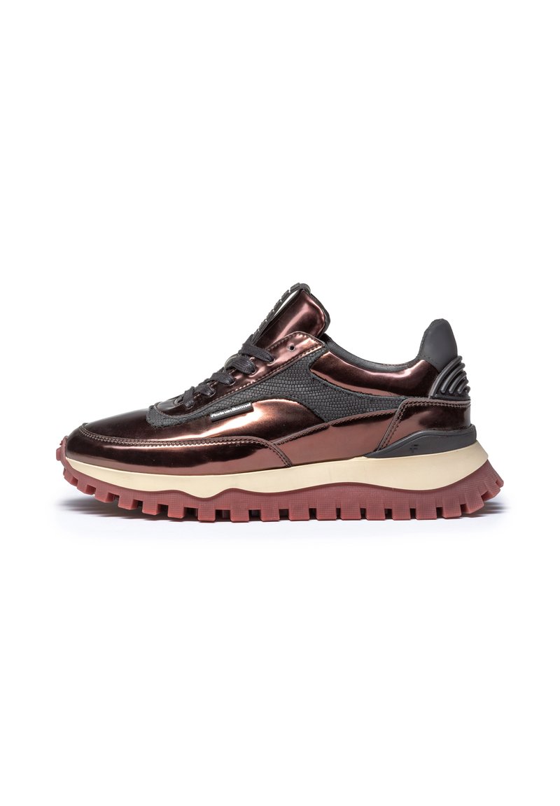 Szykowny sneaker z metaliczną brązową cholewką, siateczkowymi detalami i kontrastującymi czarnymi akcentami. Posiada grubą, teksturowaną czerwoną podeszwę.