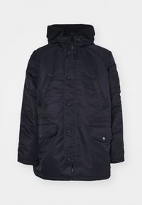 Parka negra aislante con capucha forrada de piel, cierre frontal de botones, dos grandes bolsillos laterales y un bolsillo con cremallera en la manga.