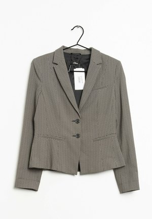 Blazer con estampado en blanco y negro, con dos botones, solapa con muesca, mangas largas y una etiqueta visible de la marca, colgado en una percha negra.
