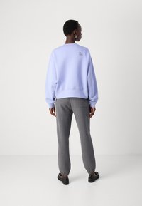 Lys lilafarget sweatshirt med ribbenmansjetter, kombinert med grå joggebukser med elastiske anklene. Enkelt design uten mønstre.