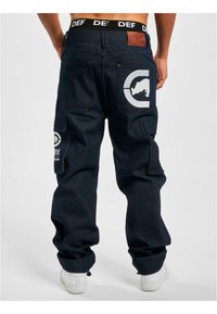 Dark denim cargo pants featuring side pockets, a logo patch on the back, and a contrasting elastic waistband with the text "DEF."