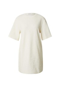 Creme-kleurige oversized t-shirt jurk van een textuurstof, met korte mouwen en een ronde halslijn. Geen patronen of accenten zichtbaar.