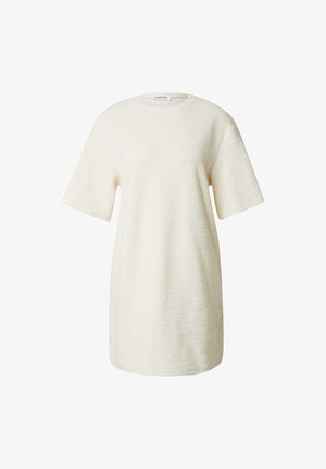 Creme-kleurige oversized t-shirt jurk van een textuurstof, met korte mouwen en een ronde halslijn. Geen patronen of accenten zichtbaar.