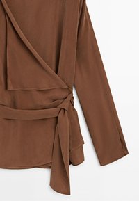Brown long-sleeve wrap blouse with side tie detail and soft, flowing fabric on a white background.