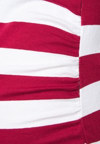 Close-up of fabric with horizontal red and white stripes, featuring a gathered seam on the right side.