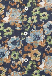 Blumenhemd mit dunklem Hintergrund, auf dem blaue, grüne und braune Blumen abgebildet sind. Knopfdetaillierung in reinem Weiß ist sichtbar.