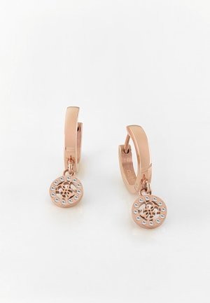 Boucles d'oreilles créoles en or rose avec pendentifs ronds présentant un motif floral découpé et un cercle de petits cristaux clairs.