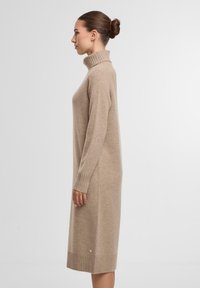 Beiges Rollkragenkleid aus weichem, strukturiertem Stoff. Verfügt über lange Ärmel, eine lockere Passform und gerippte Akzente an den Bündchen und dem Saum.