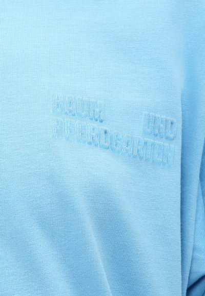 Ανοιχτό μπλε ύφασμα με ανάγλυφη, κεντημένη επιγραφή στο ίδιο χρώμα που αναγράφει "KULTUR UND PFERDEKARTHEN."