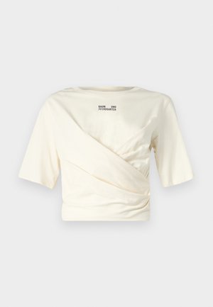 Top corto a maniche corte color crema con design drappeggiato, dotato di scollatura rotonda e stampa del logo nero ben visibile sul retro. Tessuto morbido.