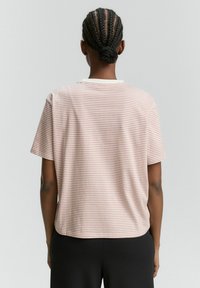 T-shirt a righe in rosa chiaro e bianco, maniche corte, scollatura rotonda, materiale in misto cotone, vestibilità morbida, dettaglio cucitura sul retro discreto.
