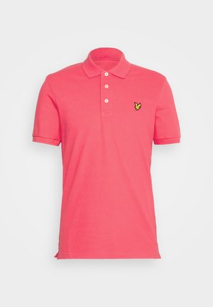 Růžové polo tričko vyrobené z bavlny, s límečkem na tři knoflíky, krátkými rukávy a malým žlutým logem na levé hrudi.