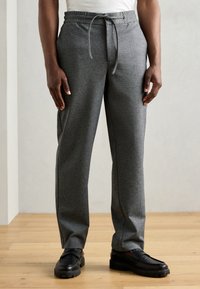 Pantaloni de trening gri, confecționați dintr-un material moale, cu talie elastică și șnur, design cu picioare drepte și buzunare laterale.